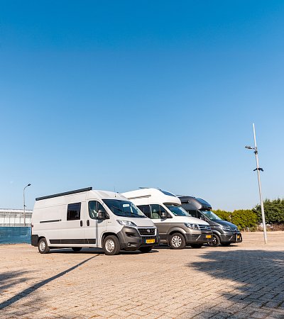 Een kleine foto van een camper met mooie blauwe lucht 